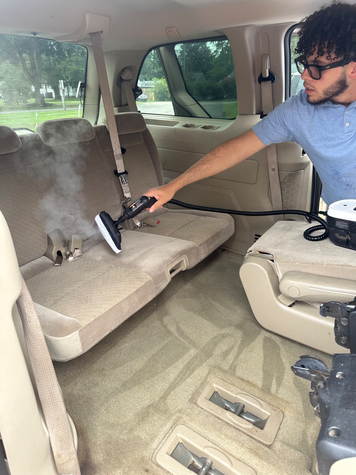 Shawn steam cleaning a minivan rear bench seat during an interior detail