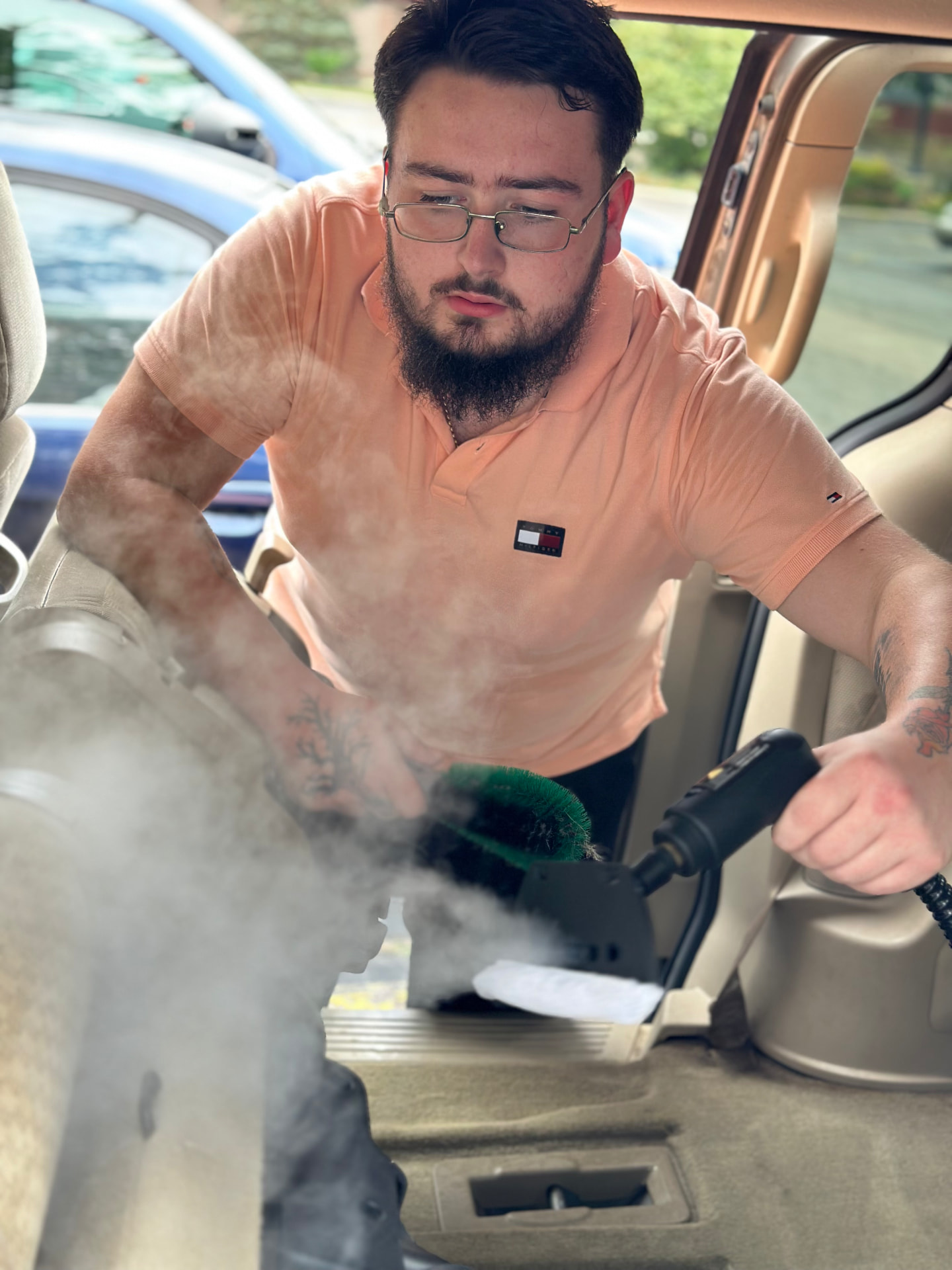 Christian steam cleaning a vehicle door sill and carpet on location